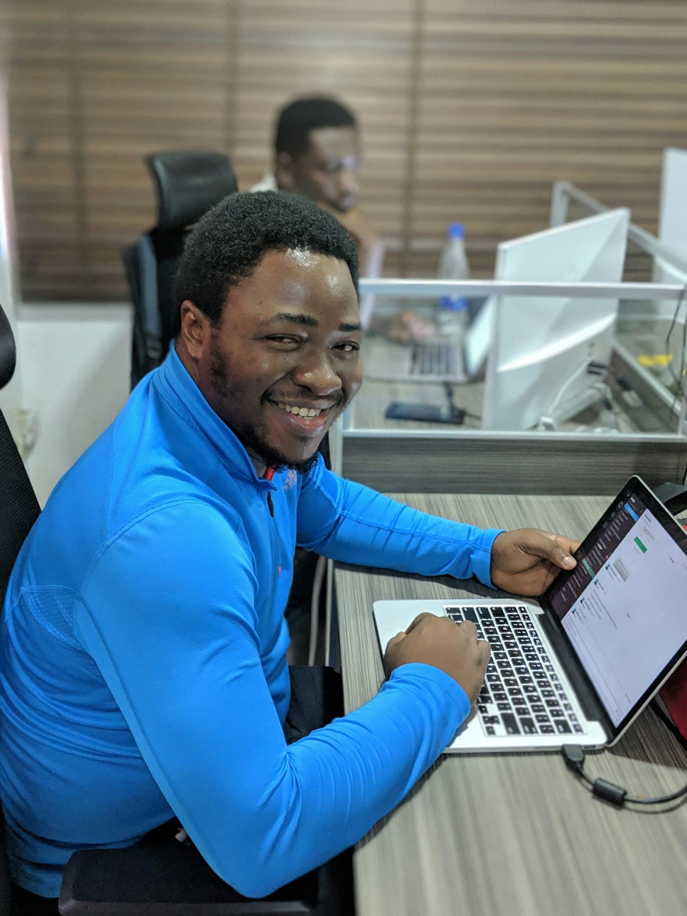 A smiling man at his desk with a laptop